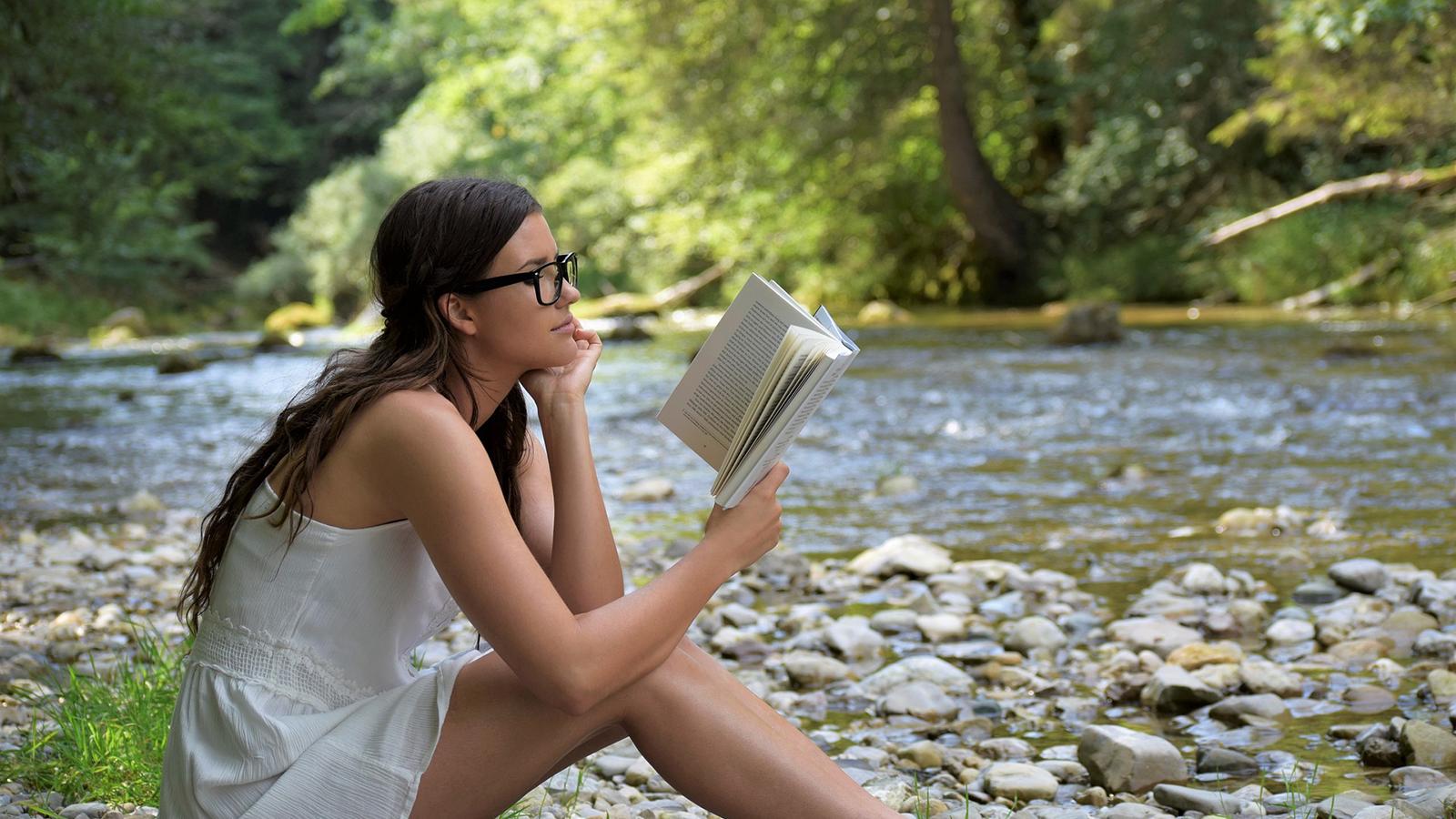 Woman Reading on Rocky Shore of Adirondack River