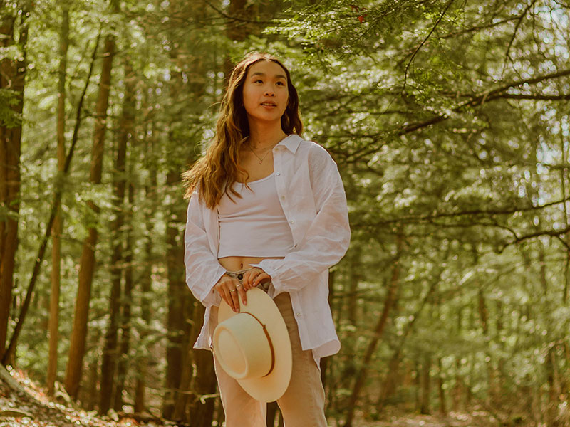 Young woman on forest path holding hat