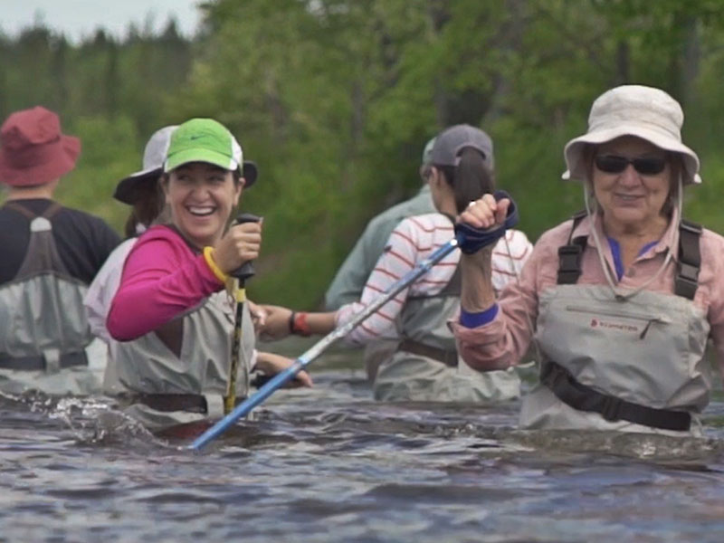 Group of people wearing waders, riverwalking in the Adirondacks.